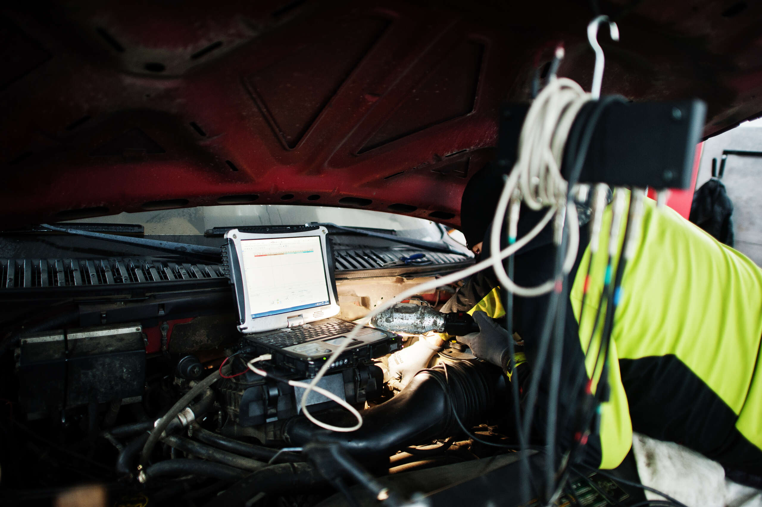 Auto mechanic diagnosing an American SUV engine with diagnostic tools, focusing on check engine light issues.