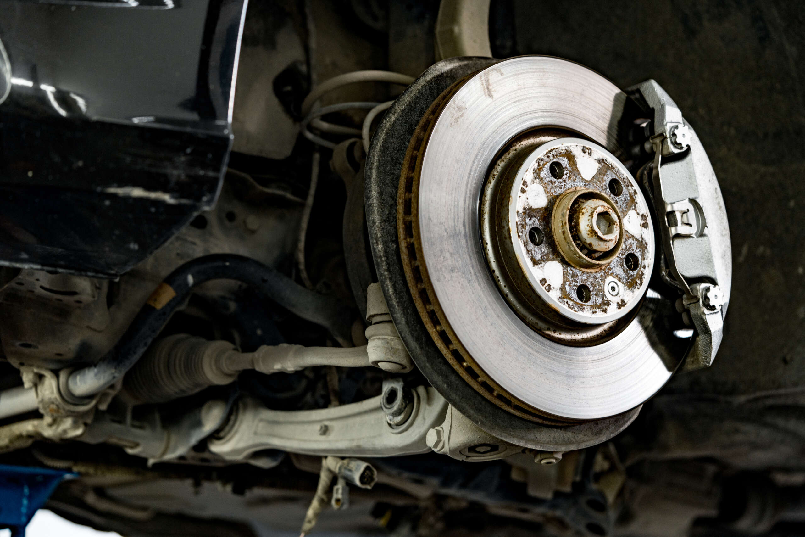 Steel brake disc and pad assembly under a vehicle, showcasing essential brake components for maintenance and repair services at Auto Star in Graham, WA.