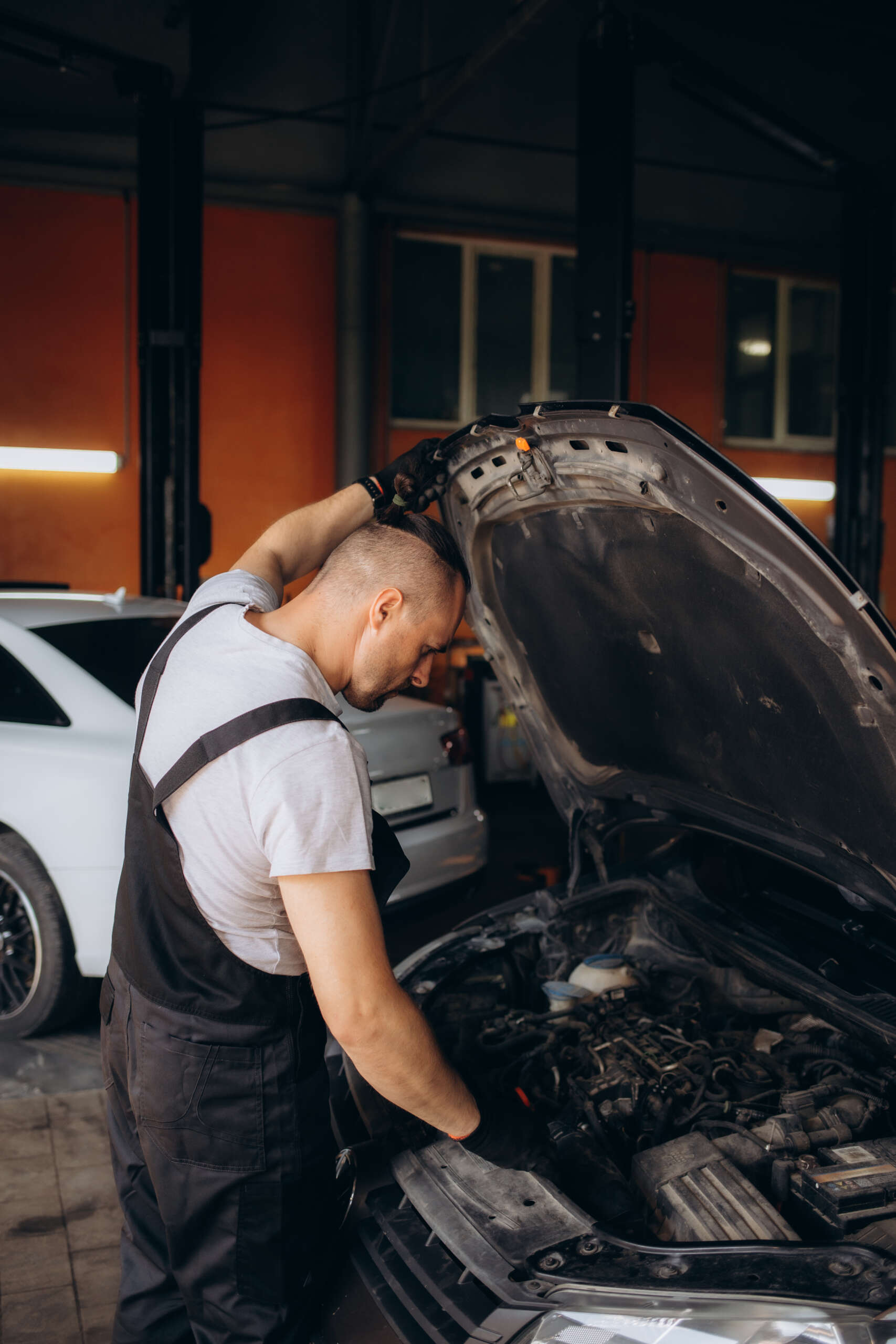 Mechanic inspecting vehicle engine in auto repair shop, highlighting transparency and expertise in vehicle services.